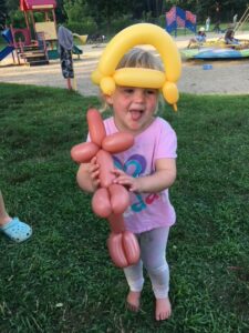 Little girl with balloon crown and dog.